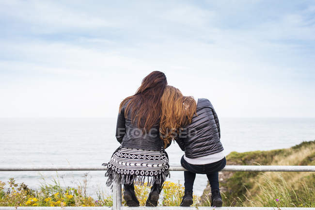 Female friends sitting on railing — Stock Photo