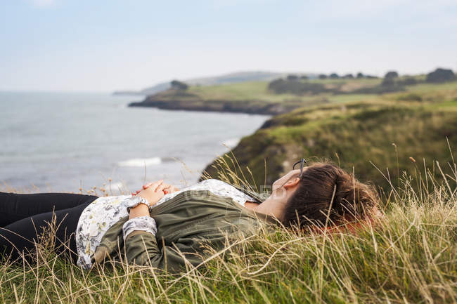 Femme couchée sur la colline herbeuse — Photo de stock