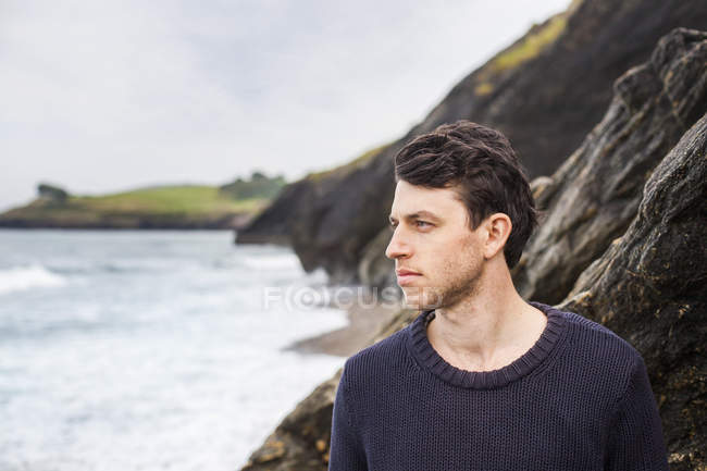 Jeune homme regardant loin de la plage — Photo de stock