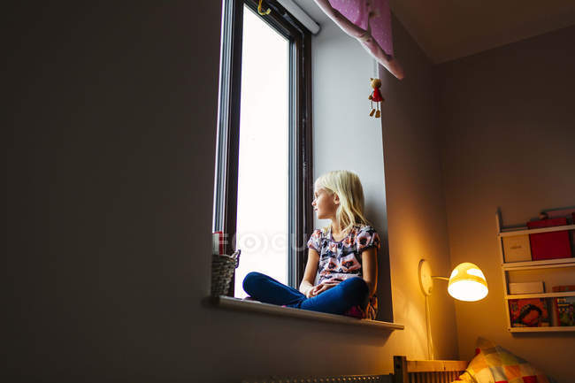 Menina olhando através da janela — Fotografia de Stock