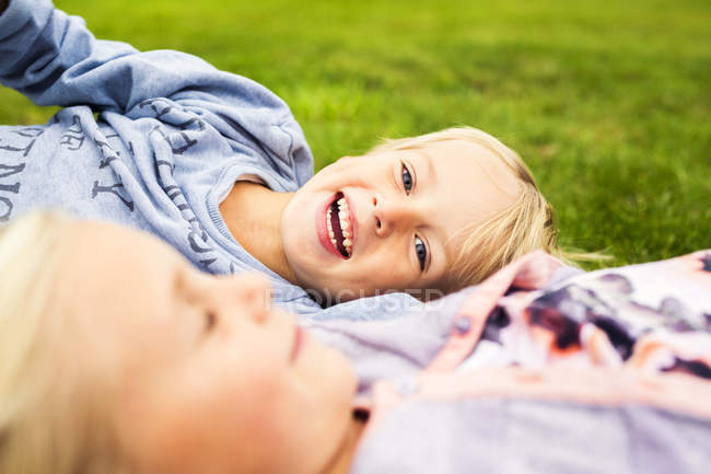 Веселий хлопчик з сестрою розслабляється у дворі — стокове фото