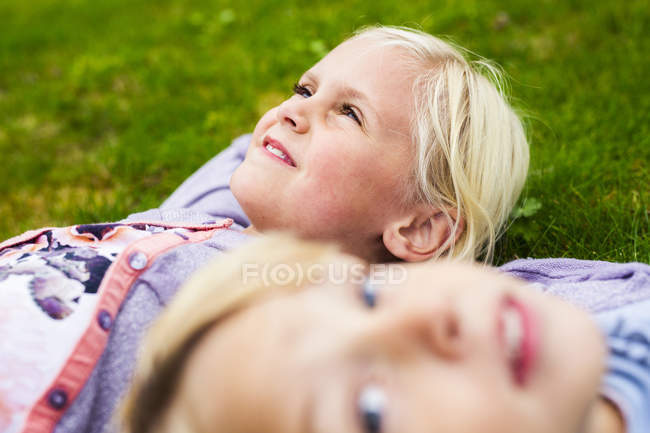 Chica con hermano acostado en la hierba - foto de stock