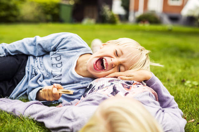 Cheerful boy lying on his sisters stomach — Stock Photo