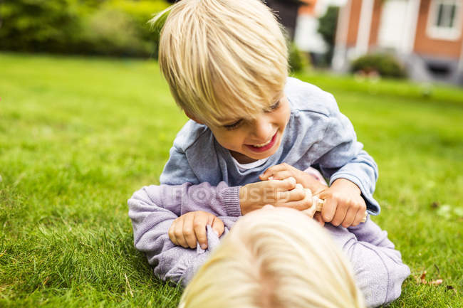 Verspieltes Geschwisterpaar im Gras liegend — Stockfoto