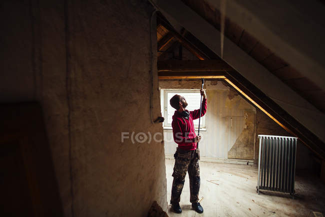 Hombre con herramienta de trabajo renovando ático - foto de stock