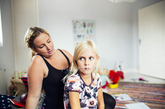 Mother making daughters hair at home — Stock Photo