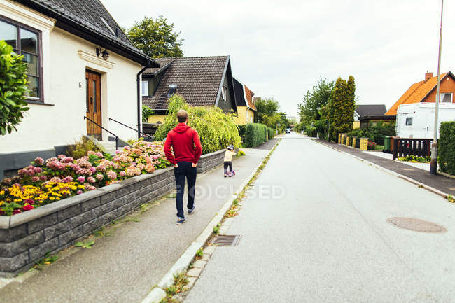 Мужчина идет по тротуару с дочерью — стоковое фото