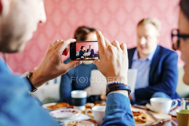 Businessman photographing colleagues — Stock Photo