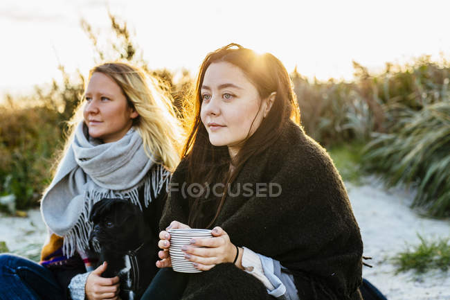 Female friends with dog on beach — Stock Photo