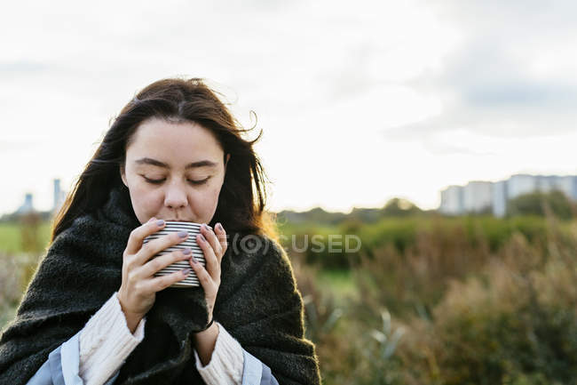 Mujer bebiendo café en la playa - foto de stock