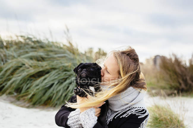 Joven mujer besando perro - foto de stock