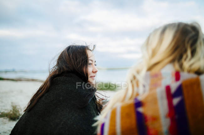 Amigos sentados en la playa - foto de stock
