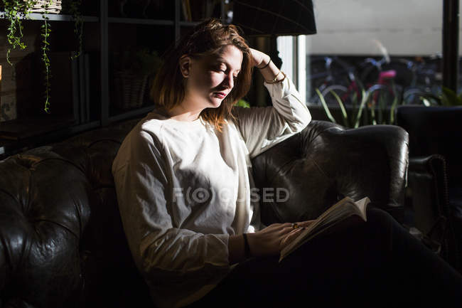 Mujer sentada en el sofá en la cafetería - foto de stock