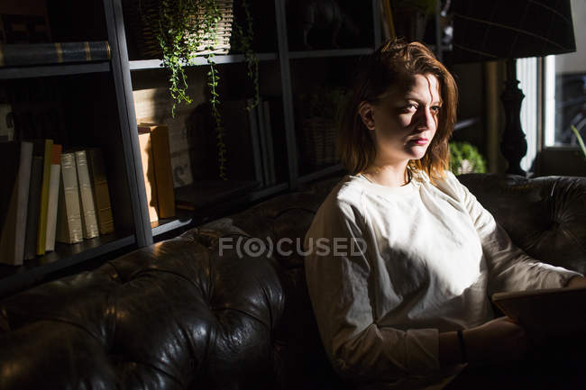 Femme assise sur le canapé au café — Photo de stock
