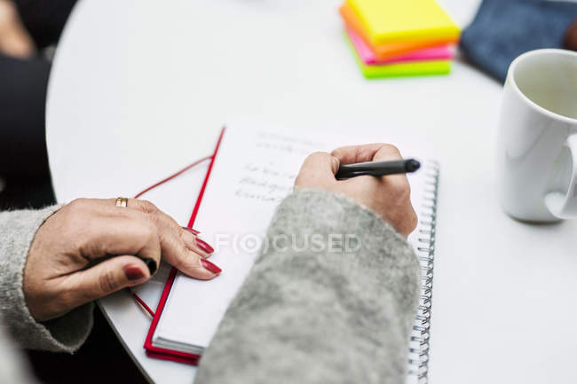 Businesswoman writing in diary — Stock Photo
