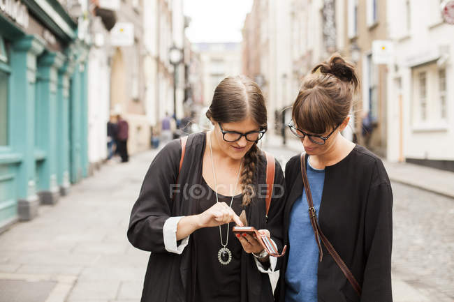 Amici di sesso femminile utilizzando smart phone — Foto stock