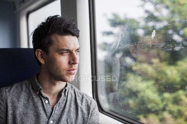 Uomo guardando attraverso la finestra del treno — Foto stock