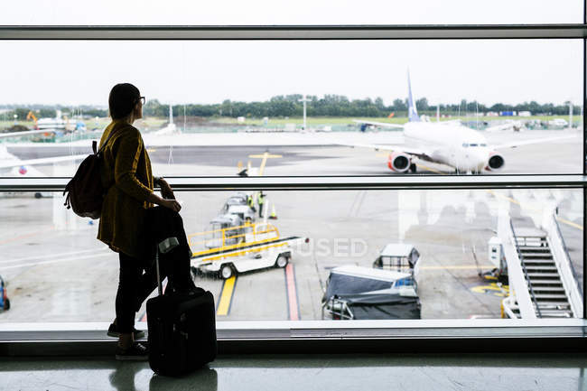 Geschäftsfrau blickt am Flughafen durch Glas — Stockfoto