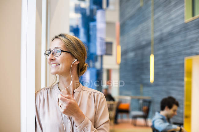 Glückliche Geschäftsfrau, die durch Fenster schaut — Stockfoto
