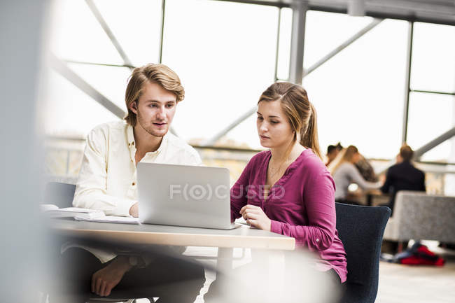 Amigos masculinos y femeninos usando ordenador portátil - foto de stock