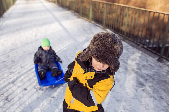 Boy pulling brother on sled — Stock Photo