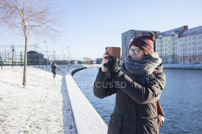 Женщина фотографирует через смартфон по каналу — стоковое фото