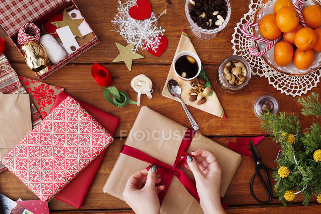 Hands tying bow on Christmas present — Stock Photo