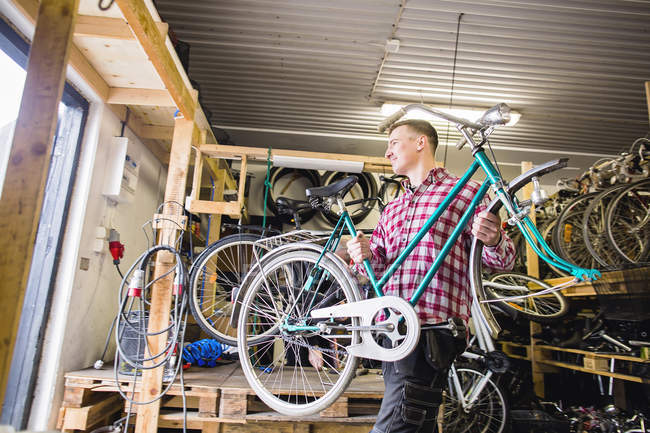 Repairman carrying bicycle in workshop — Stock Photo