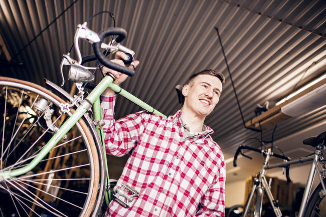 Happy mechanic carrying bicycle — Stock Photo