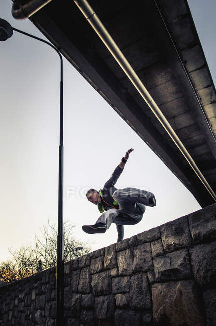 Mann springt über umliegende Mauer — Stockfoto
