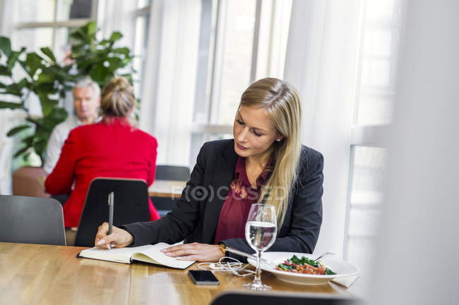 Businesswoman writing in book — Stock Photo