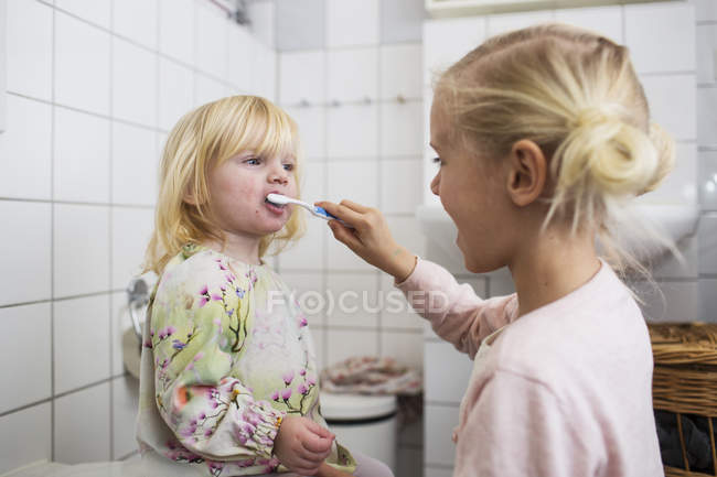 Sister brushing girls teeth — Stock Photo