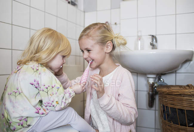 Сестры чистят друг другу зубы — стоковое фото