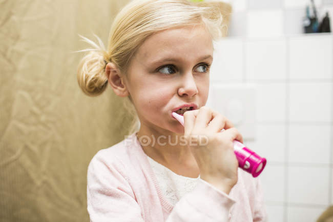 Girl brushing teeth in bathroom — Stock Photo