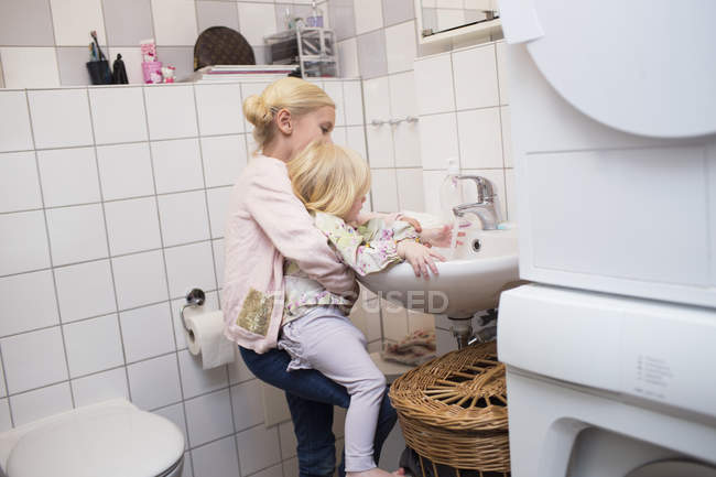 Сестра допомагає дівчині в пральній руці — стокове фото
