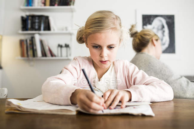 Девочка делает домашнее задание за столом — стоковое фото