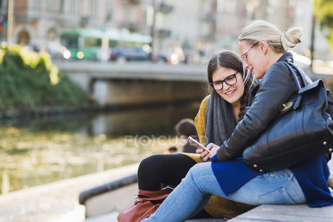 Woman showing smart phone to friend — Stock Photo