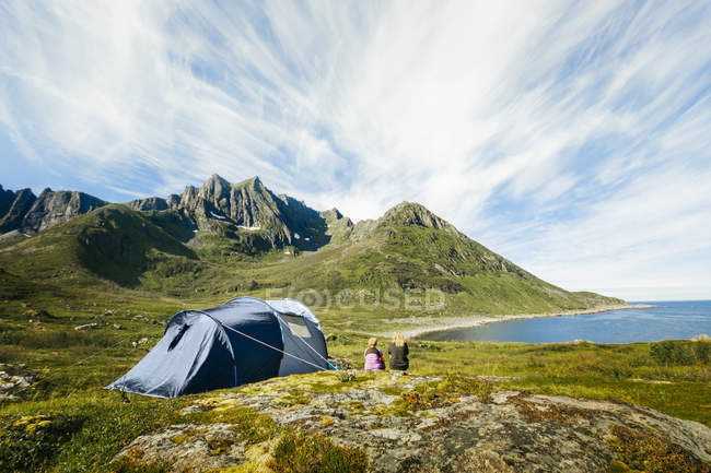 Вид сзади на людей, сидящих снаружи палатки — стоковое фото