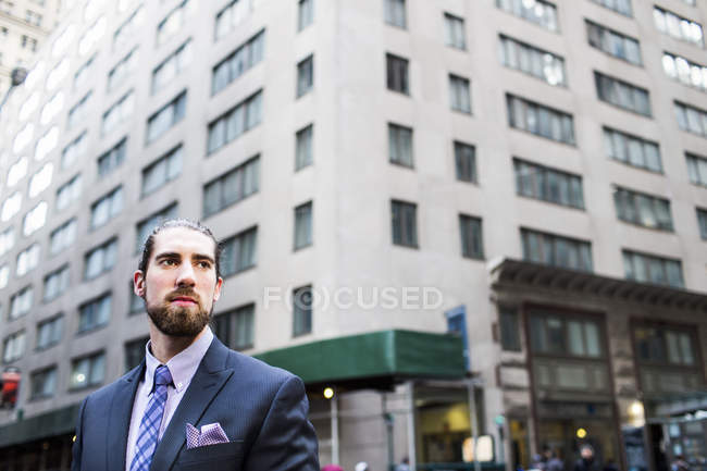 Businessman standing against buildings in city — Stock Photo