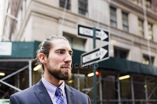 Businessman standing against buildings in city — Stock Photo