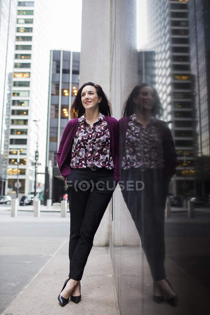 Mujer de negocios de pie en la acera por la ventana de cristal - foto de stock
