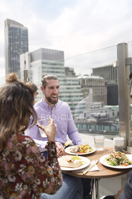 Amigos disfrutando de la comida en el restaurante de la azotea - foto de stock