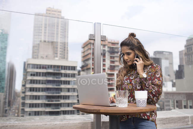 Woman using laptop at rooftop restaurant — Stock Photo
