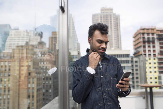 Людина використовує телефон, стоячи біля вікна на даху — стокове фото