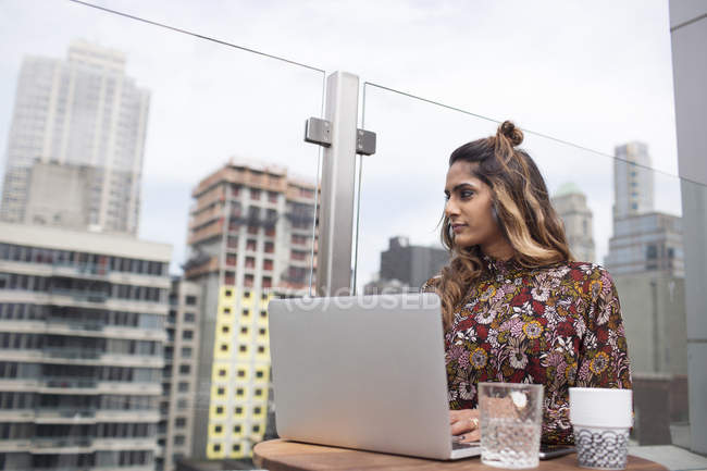 Жінка використовує ноутбук, сидячи на столі — стокове фото