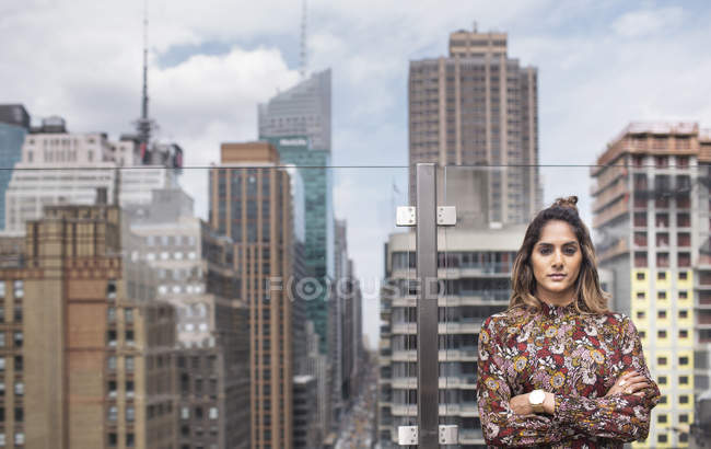 Woman standing against glass window at rooftop — Stock Photo