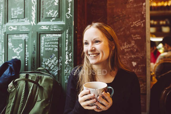 Улыбающаяся женщина держит кофе — стоковое фото