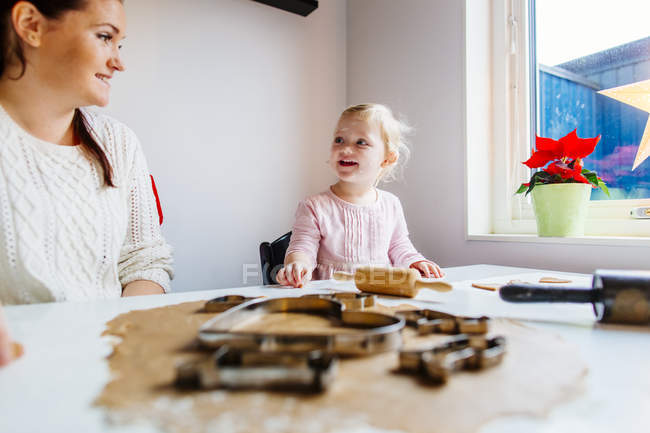 Daughter talking to mother while preparing cookies — Stock Photo