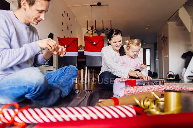 Mother and father with daughter wrapping presents — Stock Photo