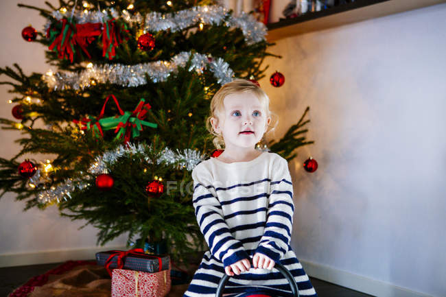 Chica jugando contra el árbol de Navidad - foto de stock